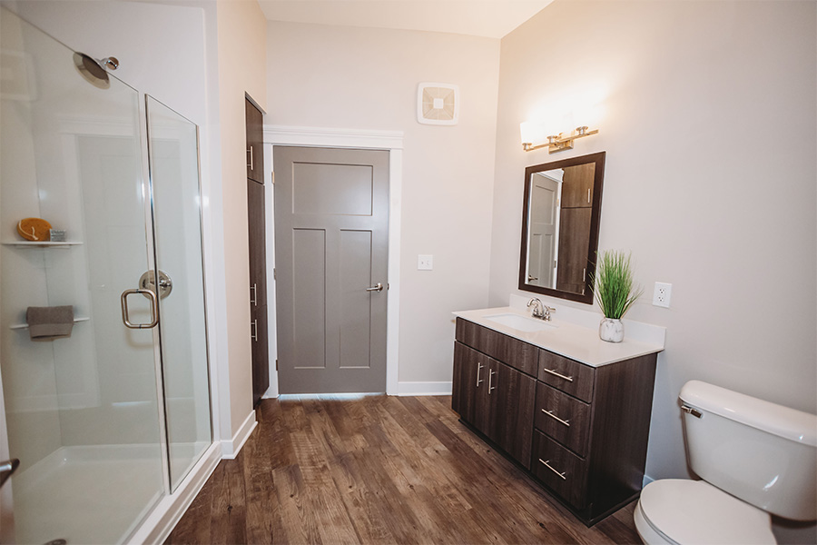 Apartment bathroom with vanity, wall mirror, and shower